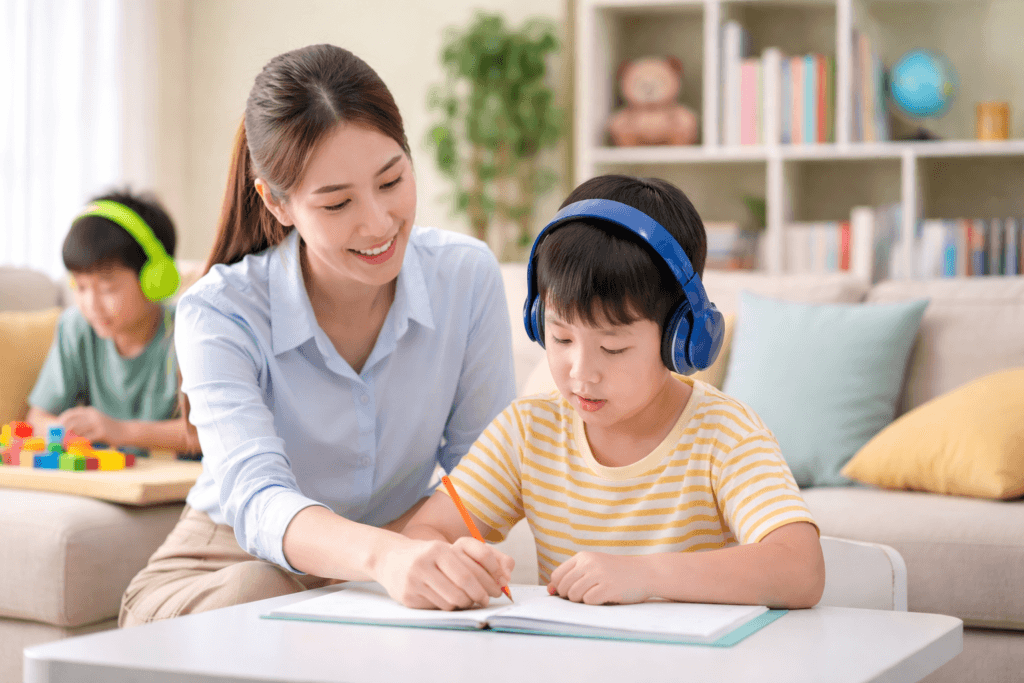 Guru privat membantu anak berkebutuhan khusus belajar menulis di rumah dengan suasana ruang tamu yang nyaman dan tenang.